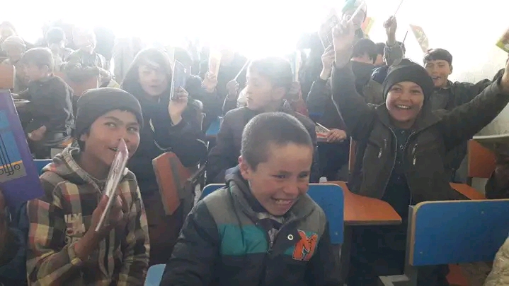 Enfants afghans étudiant dans une salle de classe baignée de lumière